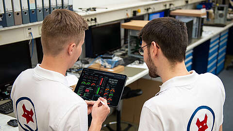 Zwei LEITDESK-Mitarbeiter schauen sich Kennzahlen auf einem Tablet