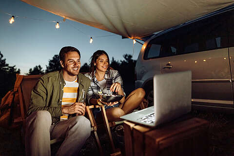 Ein Paar campt und schaut auf einen Laptop