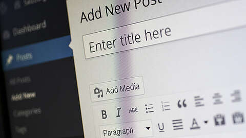 Ein Computerbildschirm, der eine WordPress-Editor-Seite mit der Aufforderung "Geben Sie hier den Titel ein" zum Erstellen eines neuen Blogbeitrags anzeigt, und darunter sichtbare Formatierungsoptionen.