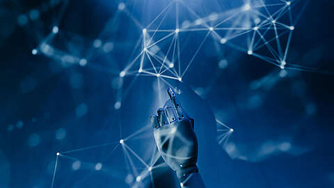 Eine Roboterhand streckt sich nach oben zu einem Netzwerk aus leuchtenden, miteinander verbundenen Knoten und Linien, die auf blauem Hintergrund Technologie, KI und digitale Konnektivität symbolisieren.
