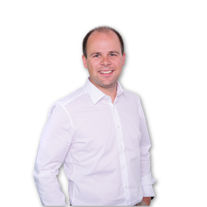 Ein lächelnder Mann mit kurzen Haaren trägt ein weißes Button-up-Hemd und steht vor einem hellgrauen Hintergrund.